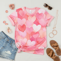 Watercolor hearts print short sleeve t-shirt in pink coral and peach tones - styled flat lay with denim shorts and rose gold accessories